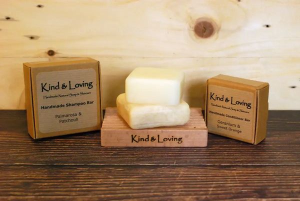 shampoo and conditioner bars on a wood soap dish bars packaged in recycleable kraft boxes 