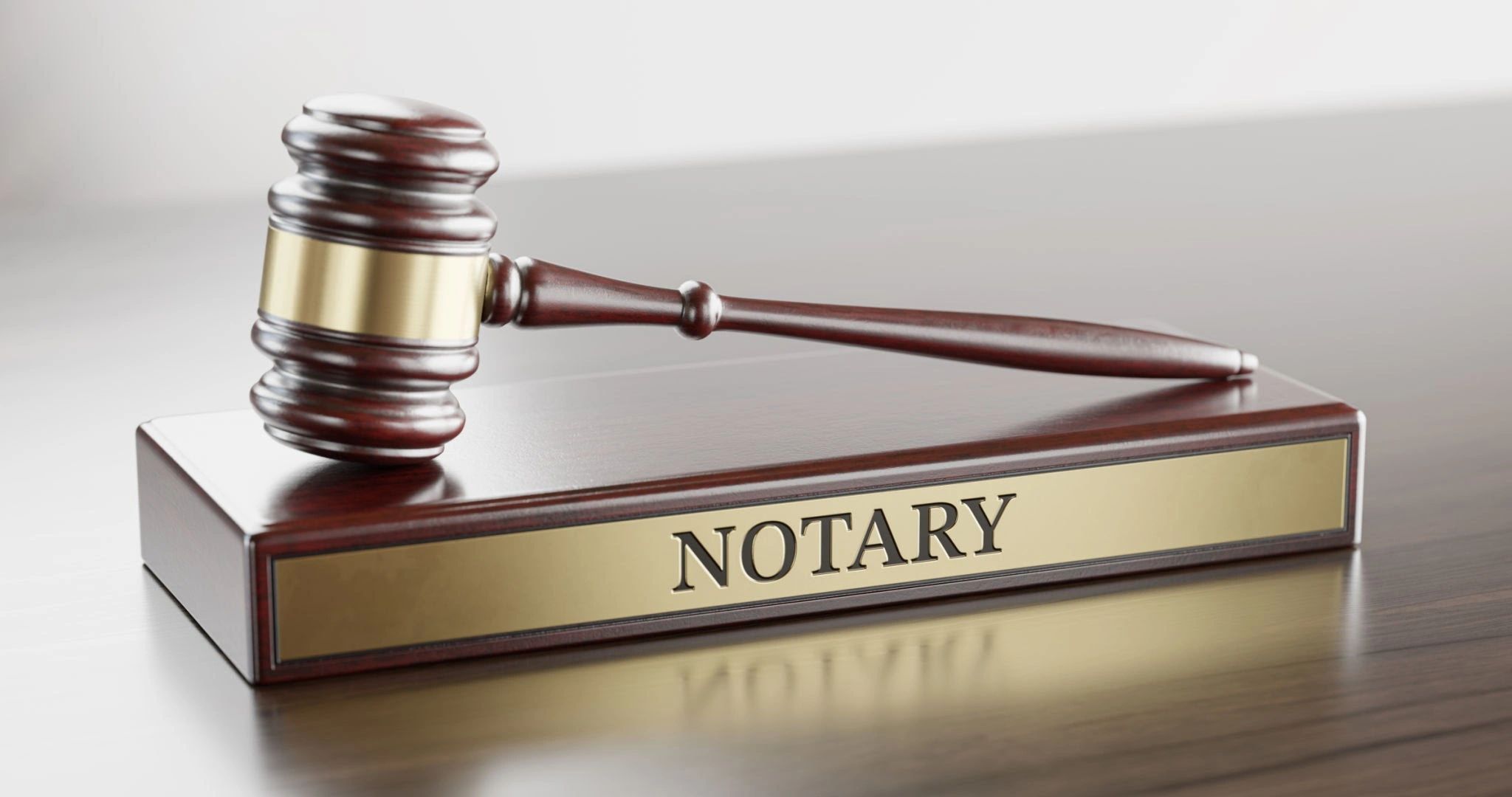A wooden gavel resting on a notary nameplate.
