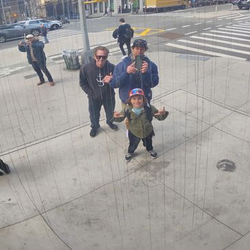 Three people and a child taking a selfie in a reflective sculpture on a city sidewalk.