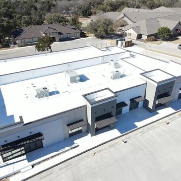Aerial view of a modern white commercial building flat roofing system by Waterproof roofing.