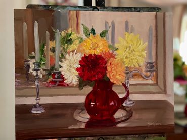 red glass vase, dahlia flowers, tall white candles on wood dresser