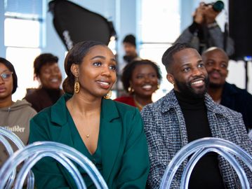 Audience members attentively watch a presentation or event indoors.