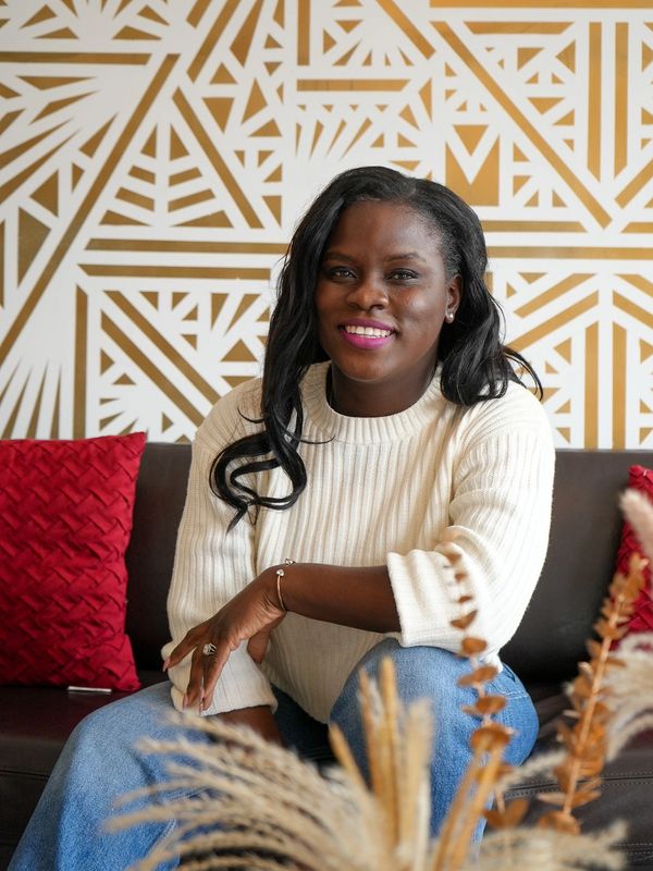 Smiling woman in a white sweater sitting on a couch.