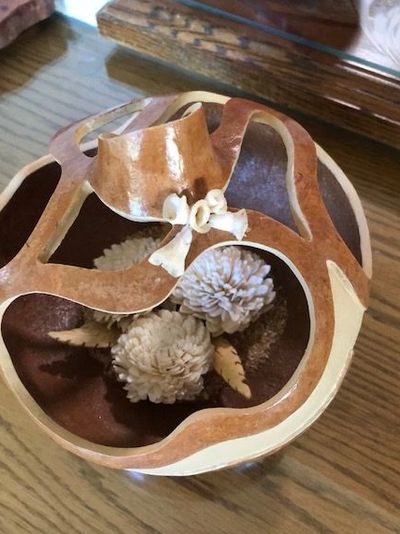 Decorative carved wooden bowl with floral ornaments inside, on a wooden table.