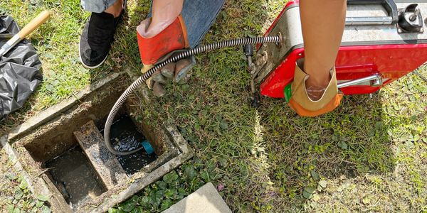 using a snake to run through a drain to unclog a clogged residential runoff drain.