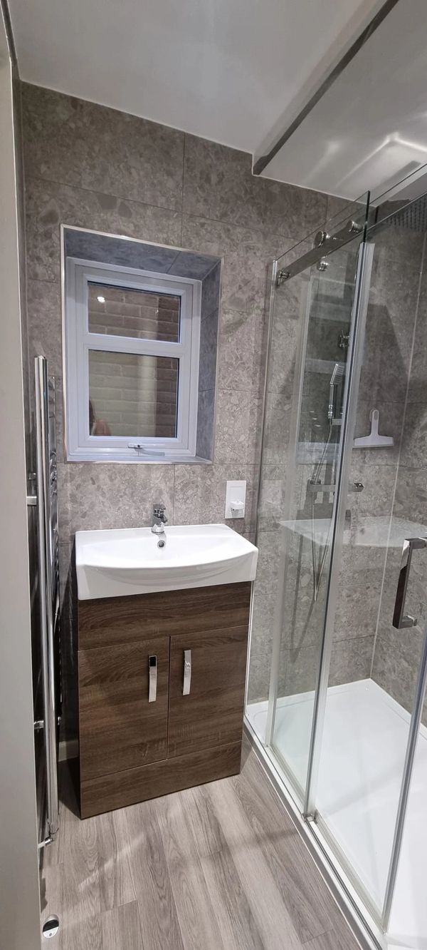 Modern bathroom with sink, storage cabinet, and glass shower enclosure.