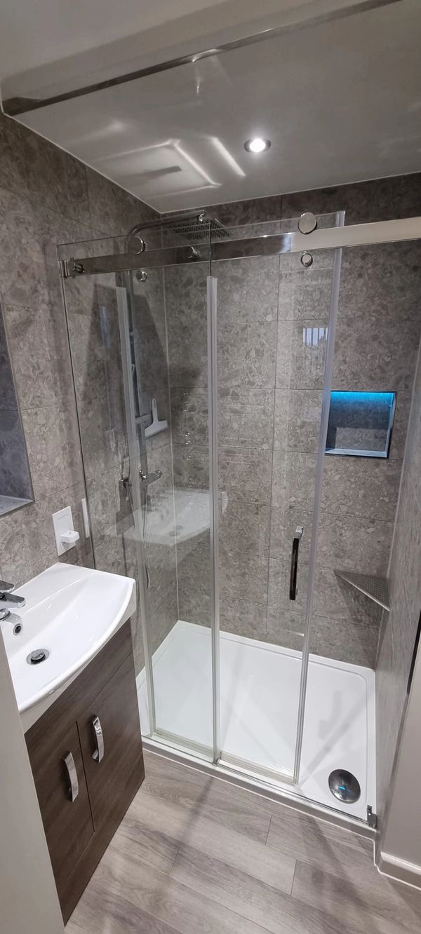 AFTER: Stylish new ensuite featuring a sliding glass shower door, illuminated shower niche, basin, W