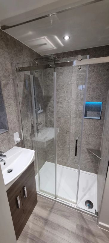 Modern bathroom with glass shower enclosure and wooden vanity.