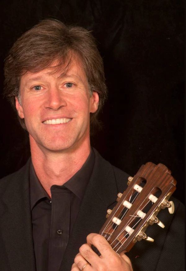 Smiling man holding a guitar.