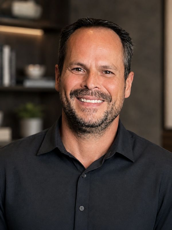 Smiling man with short dark hair and a beard in a black shirt.