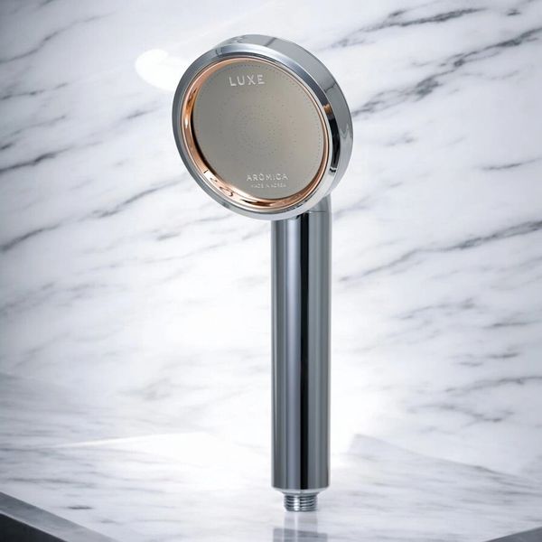 Sleek chrome shower head with a luxurious design against a marble background.