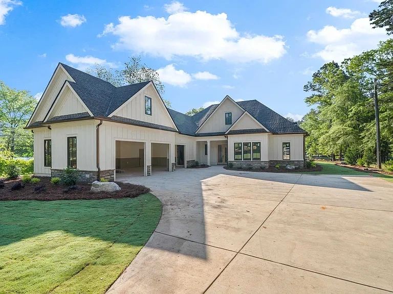 Modern white house with a spacious driveway and garage under a blue sky.
