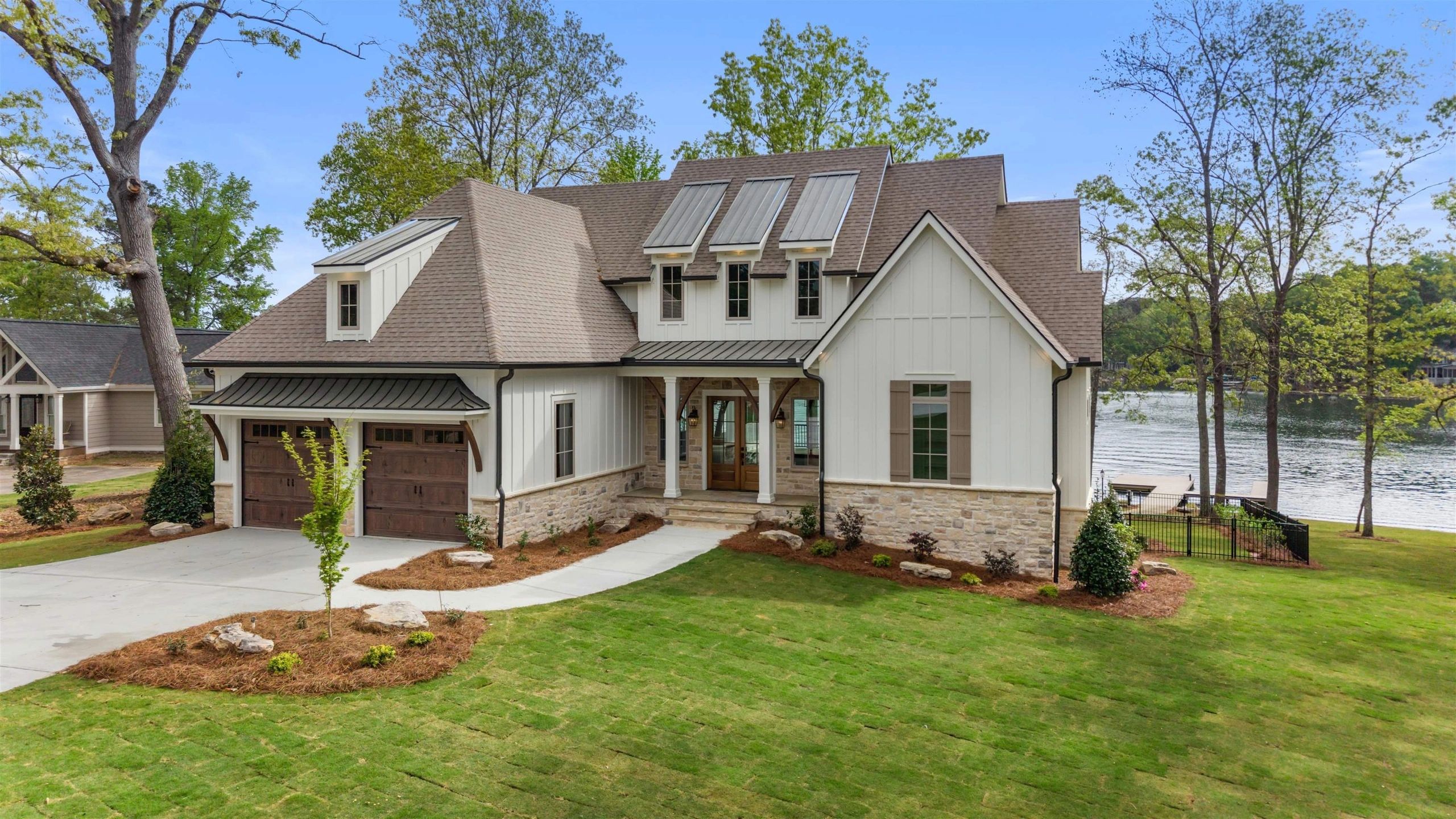 Modern lakefront house with large garage and manicured lawn.