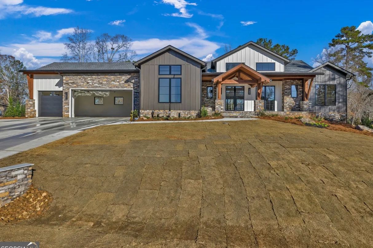 Modern house with stone and wood accents under a bright blue sky.