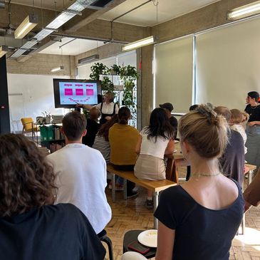 Workshop presenter delivering a talk to an engaged group in a modern, informal learning space