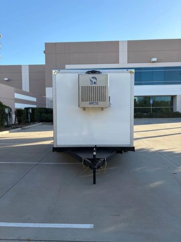 White refrigerated trailer parked outside a building.
