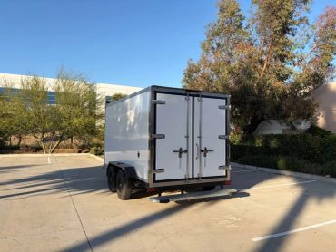 White enclosed trailer parked in a sunny lot.