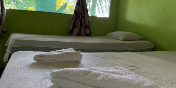 Habitación sencilla con dos camas y toallas blancas.