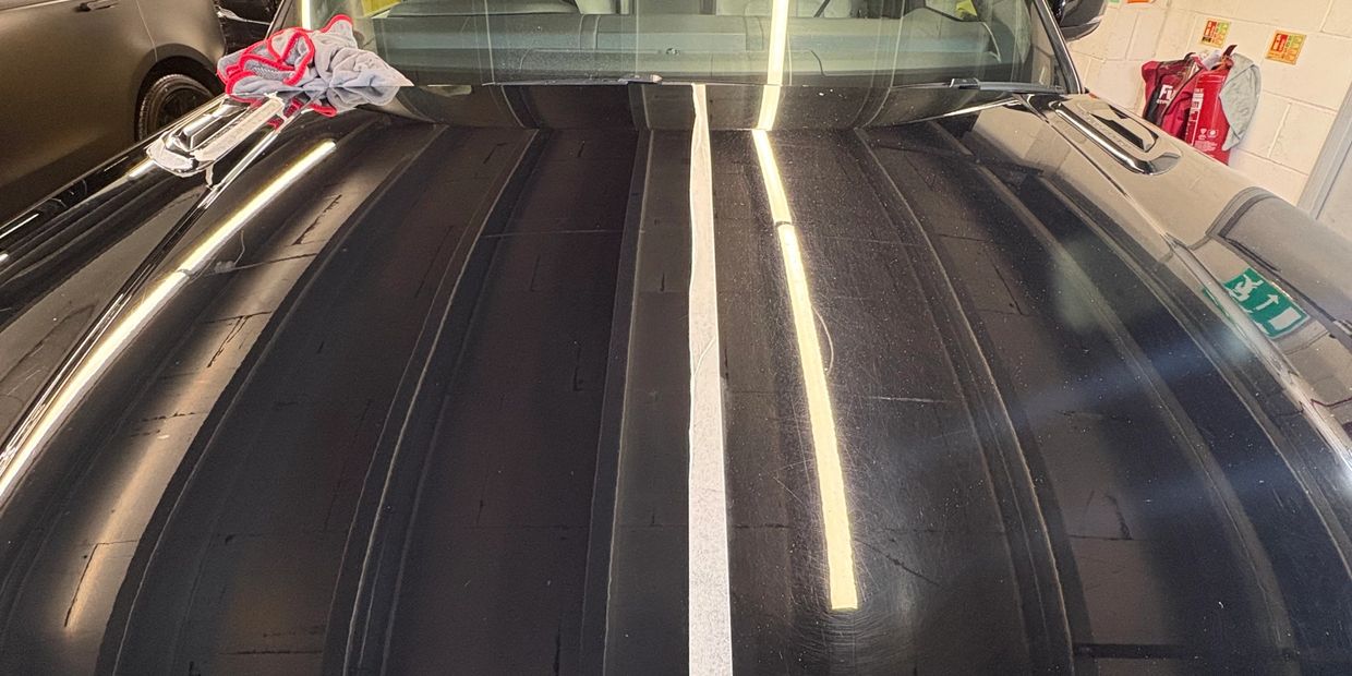 Car hood showing a before and after cleaning effect.