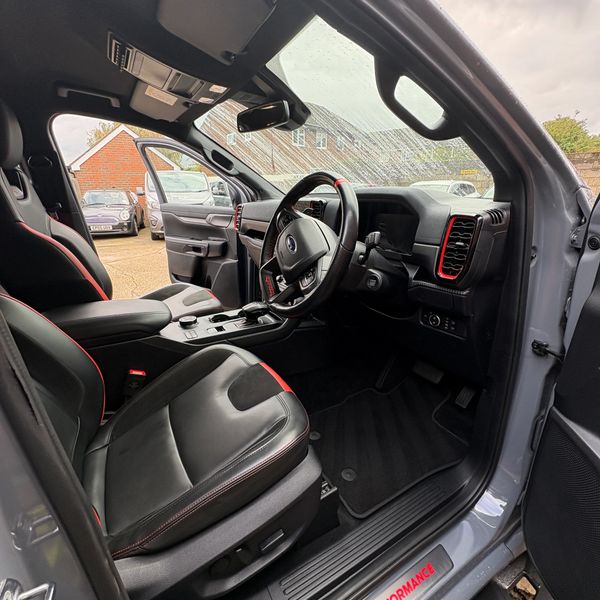 Interior of a sporty car with black leather seats and red accents.