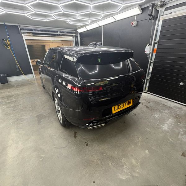 Sleek black SUV parked inside a modern, well-lit garage with hexagonal ceiling lights.