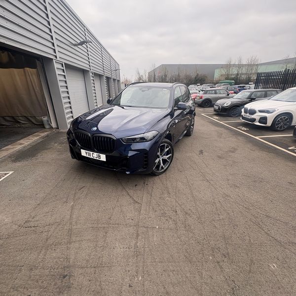 Dark blue BMW SUV parked outside a garage on a cloudy day.