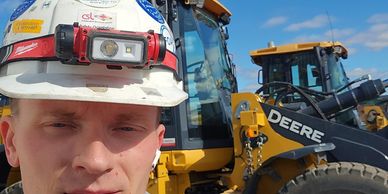 Man in a construction helmet taking a selfie at a construction site.