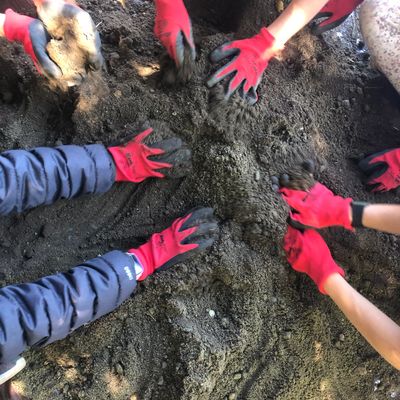 Youth participants in the program are wearing red gloves and mixing the cobb by hand.