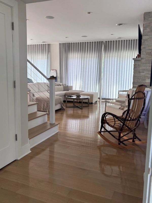 Modern living room with wooden rocking chair and light-filled space.