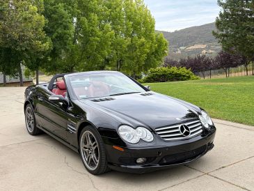 Black Mercedes convertible with red interior parked outdoors.