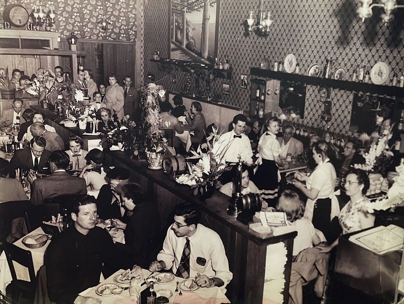 A busy vintage restaurant filled with diners and servers.