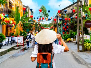 A tourist lady walking through the colorful Hoi An streets's ancient town.