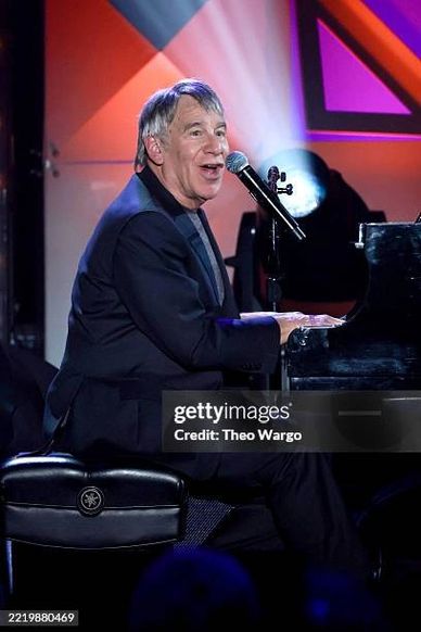 Musician playing piano and singing into a microphone.