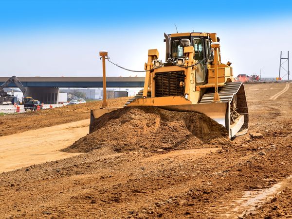 Bulldozer leveling dirt on new road