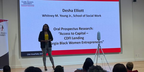 Woman presents research presentation on stage in front of large audience.
