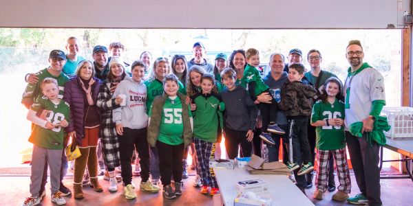 Group photo of diverse people indoors, many wearing sports jerseys.