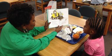 Member Mary Ann Collier reads to an elementary student.