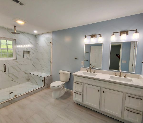 Modern bathroom with glass shower and double sinks.