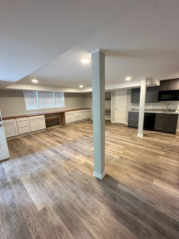 Spacious basement with wood flooring and cabinetry.