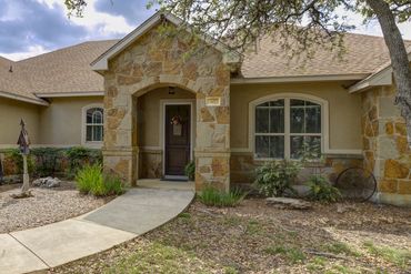 Stone and stucco house entrance with arched doorway and landscaped yard.