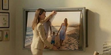 Businesswoman adjusting a large family photo in an office.