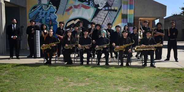 A group photo of a band with various musical instruments outdoors.