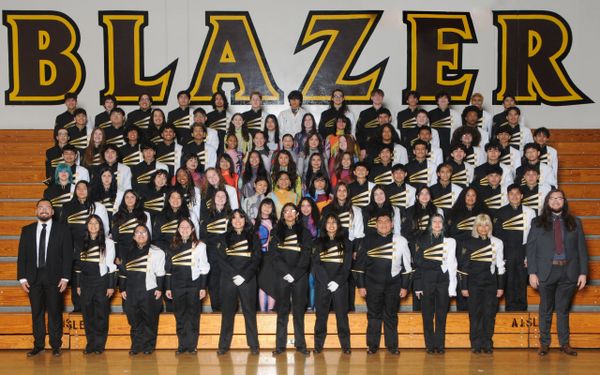 High school band group photo in uniform under "BLAZER" sign.