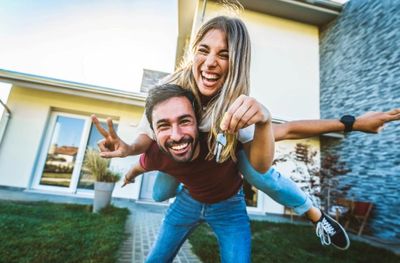 Happy couple celebrating with house keys outside their new home.
