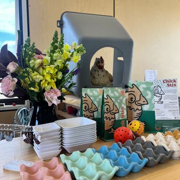 Colorful eggs, tissue boxes, flowers, and a gray object on a table.