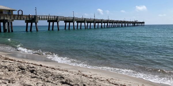 Long pier extending over calm ocean waters on a sunny day.