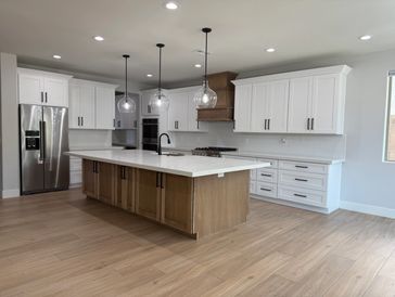 Modern kitchen with white cabinets, wooden island, and stainless steel appliances.