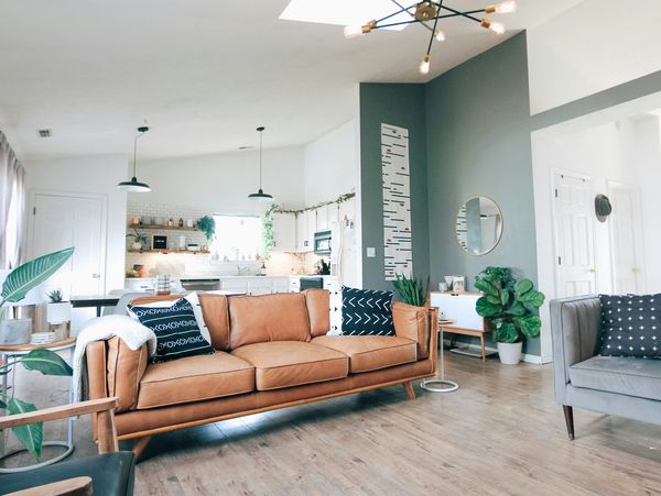 Modern living room with tan sofa and open kitchen design.