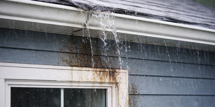 Water leaking from a damaged gutter on a house.