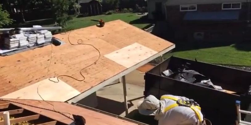 Roofing work in progress with materials and a worker on the wooden roof.